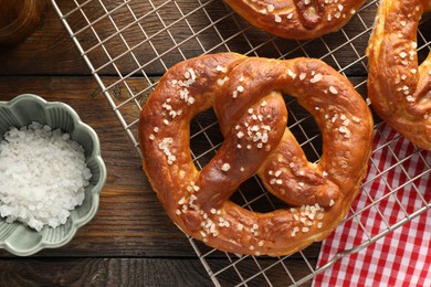 Photo of Tasty pretzels with salt on wooden table, flat lay