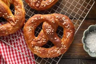 Photo of Tasty pretzels with salt on wooden table, flat lay