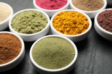 Photo of Different superfood powders on black table, closeup