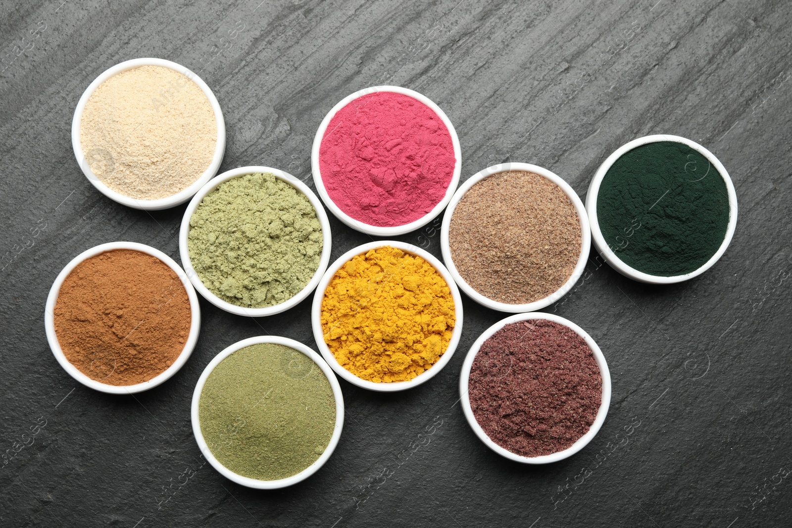 Different superfood powders on black table, flat lay Photo of Different superfood powders on black table, flat lay