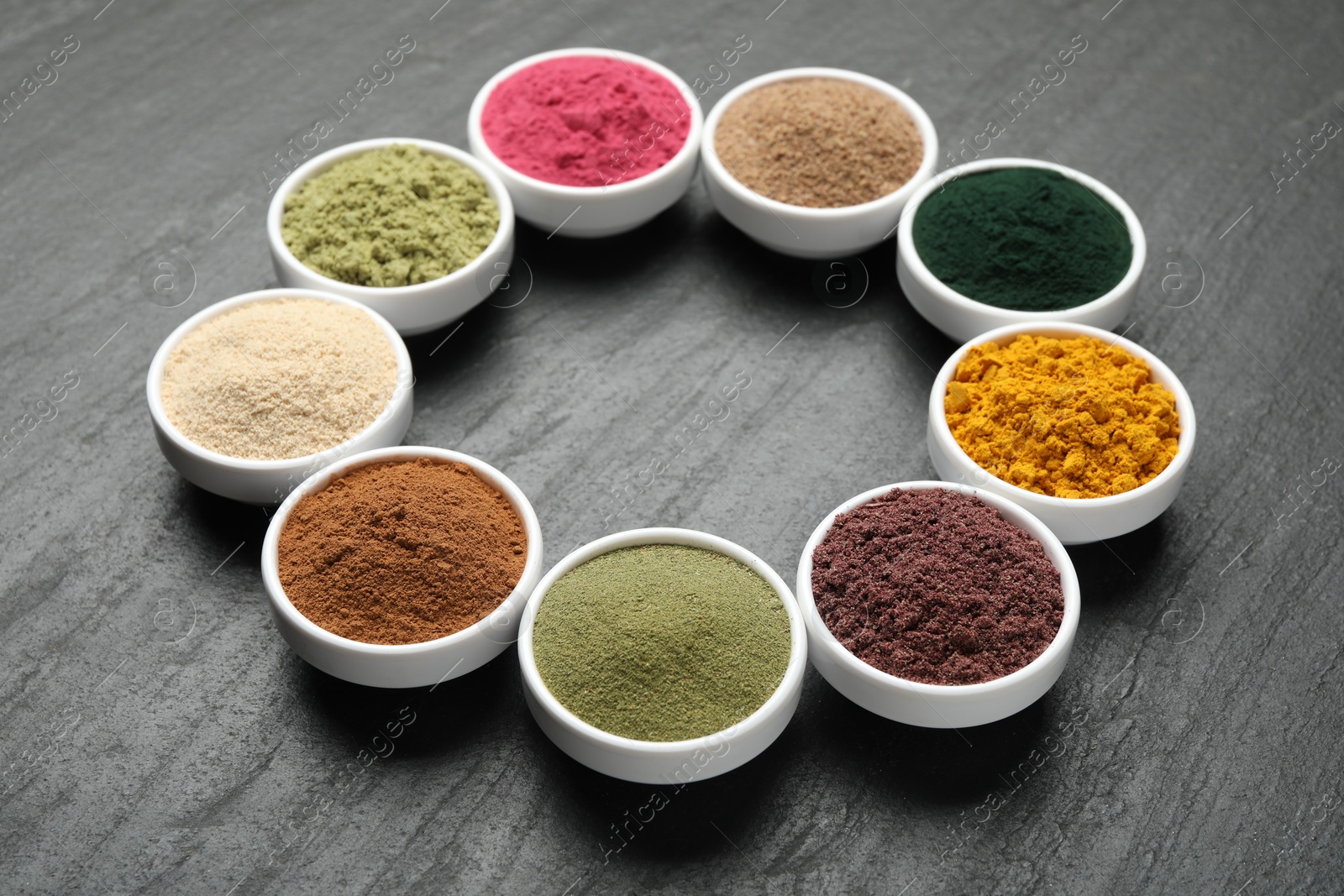 Different superfood powders in bowls on black table Photo of Different superfood powders in bowls on black table