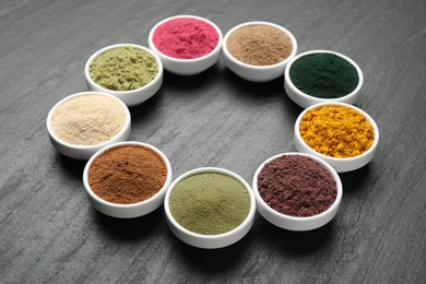 Photo of Different superfood powders in bowls on black table