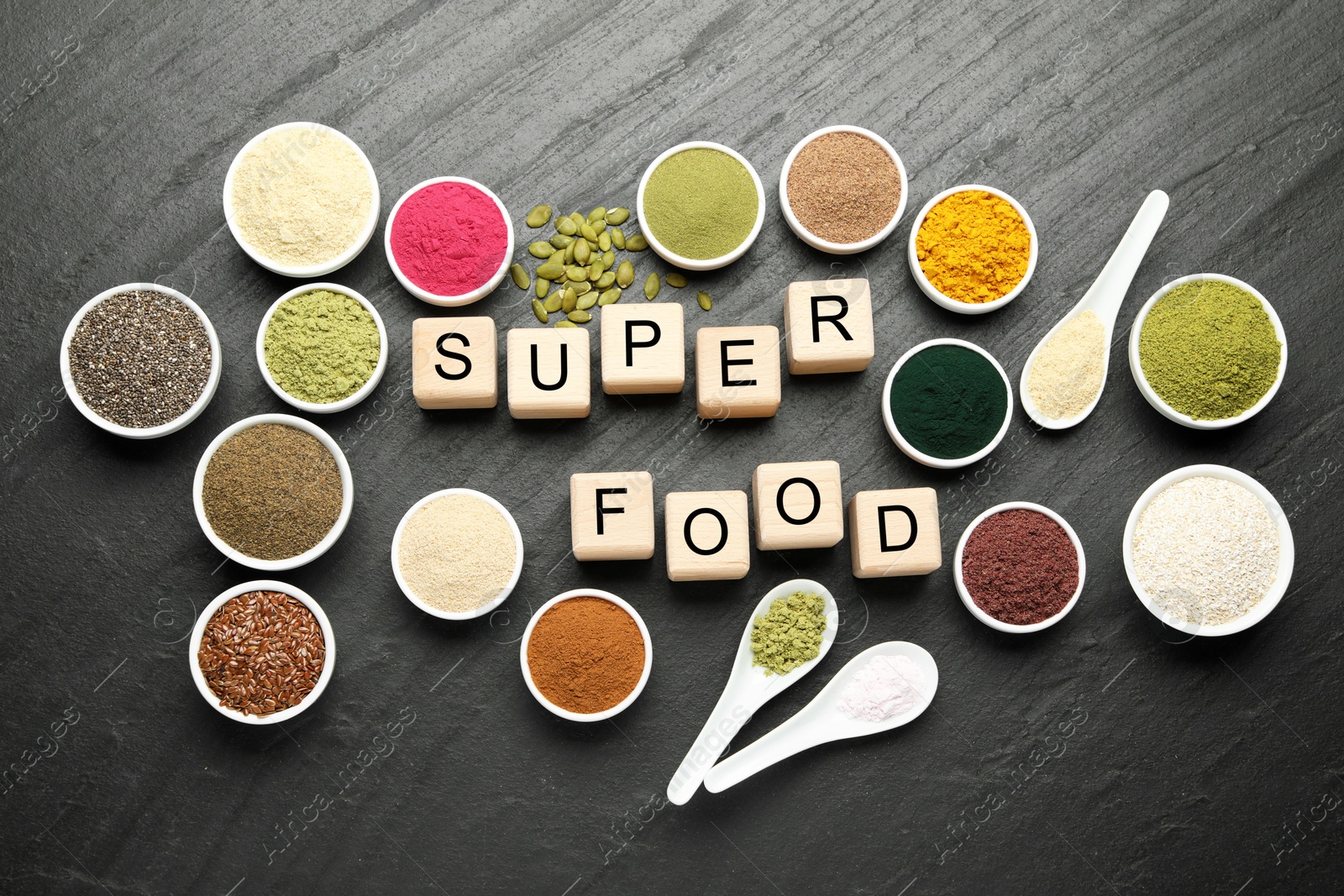 Different superfood powders and words made of cubes on black table, flat lay Photo of Different superfood powders and words made of cubes on black table, flat lay