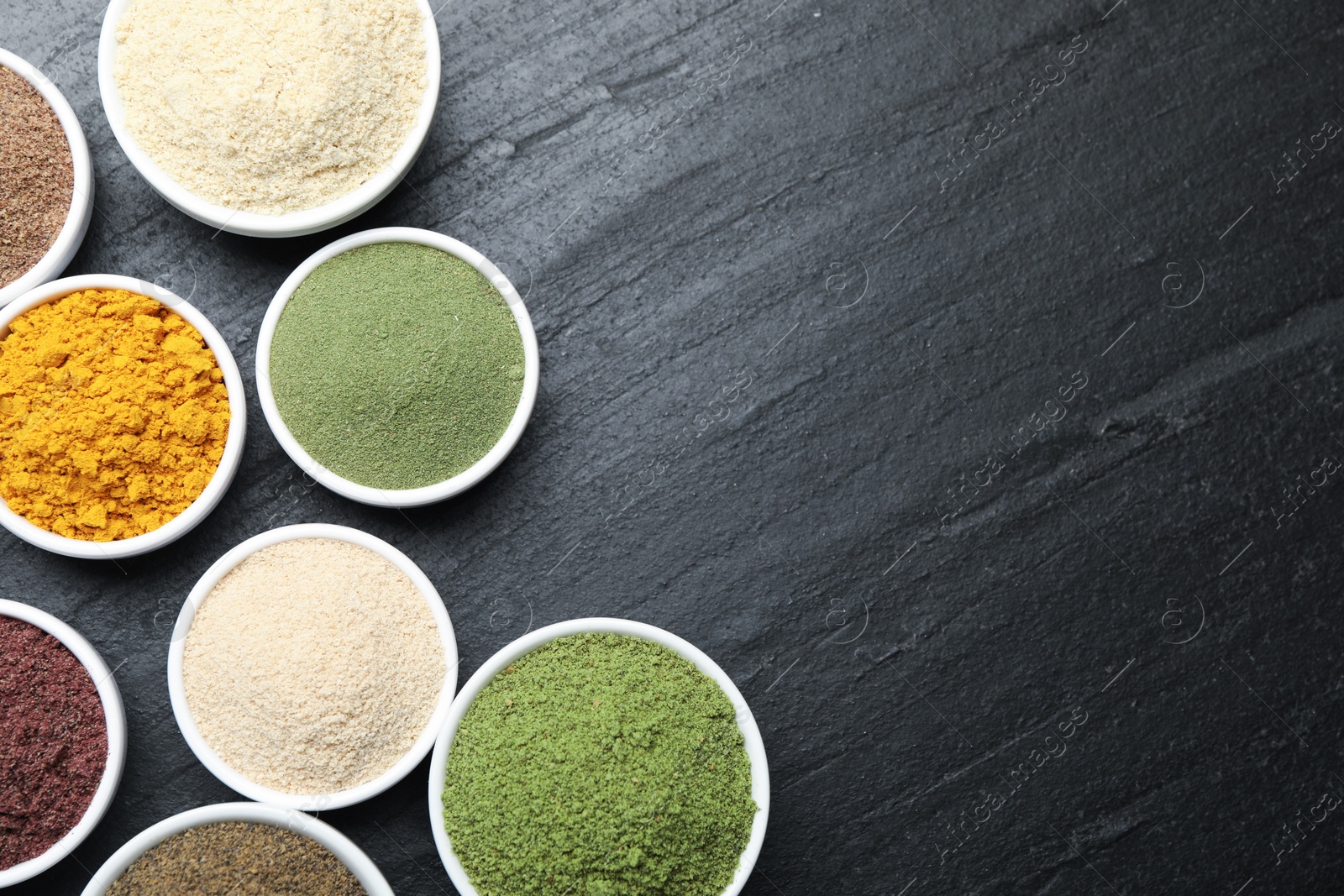 Different superfood powders on black table, flat lay. Space for text Photo of Different superfood powders on black table, flat lay. Space for text