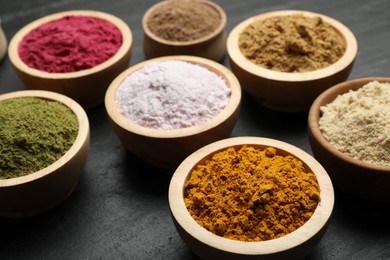 Photo of Different superfood powders on black table, closeup