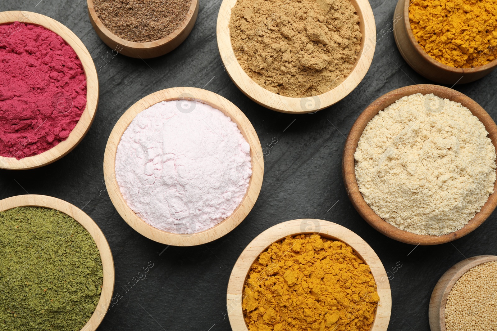 Different superfood powders on black table, flat lay Photo of Different superfood powders on black table, flat lay