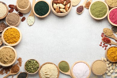 Photo of Frame of different superfood powders on light grey table, flat lay. Space for text