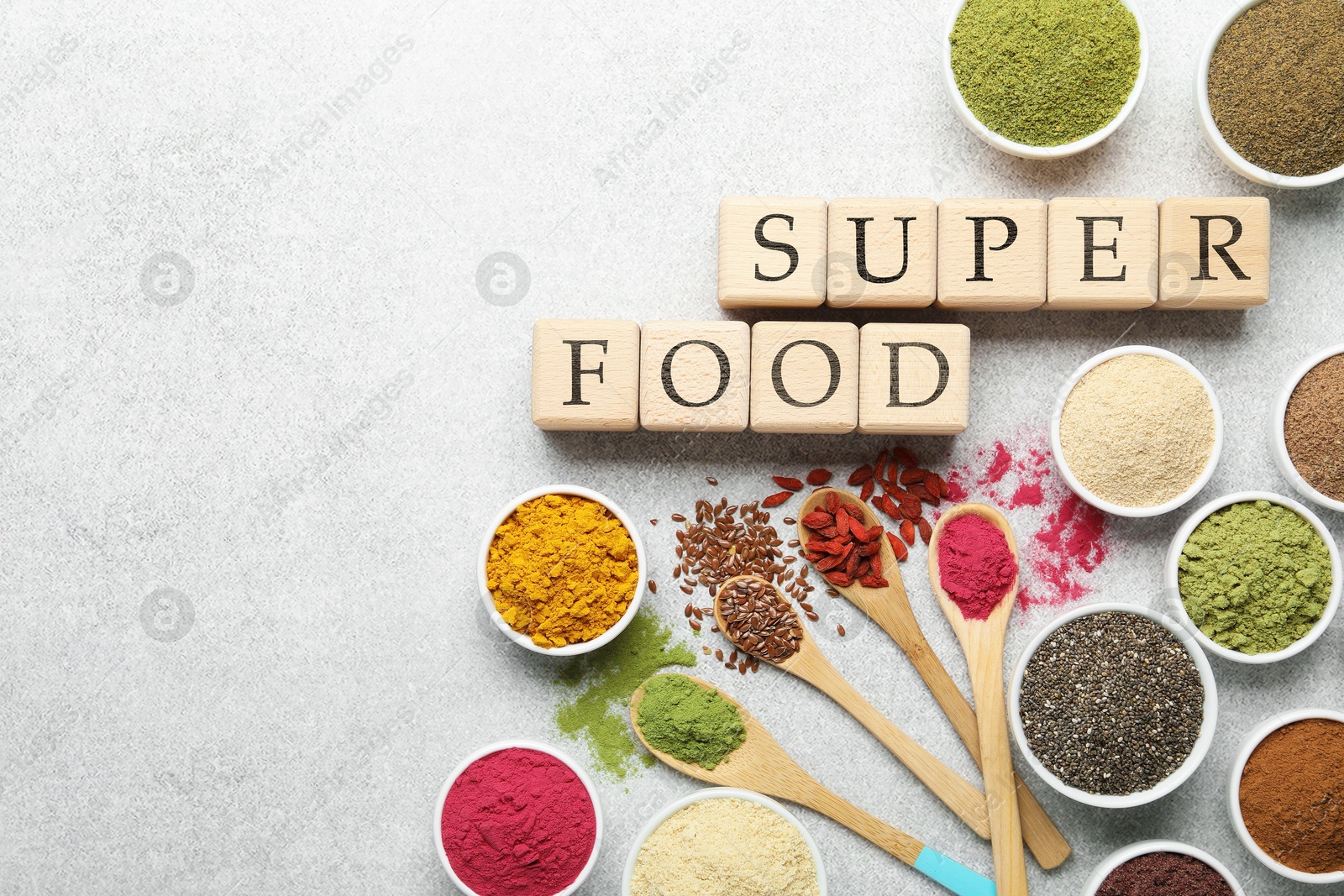 Photo of Different superfood powders and words made of cubes on light grey table, flat lay. Space for text
