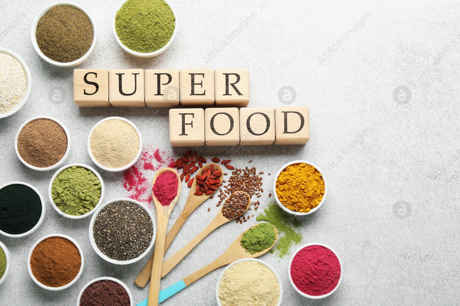 Photo of Different superfood powders and words made of cubes on light grey table, flat lay. Space for text