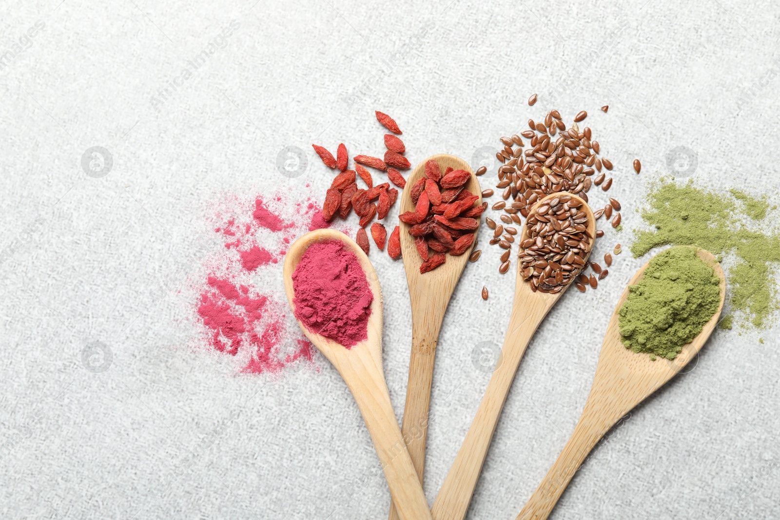 Different superfood powders in spoons on light grey table, flat lay Photo of Different superfood powders in spoons on light grey table, flat lay