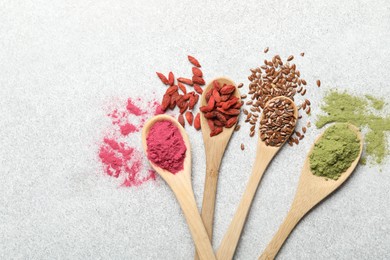 Photo of Different superfood powders in spoons on light grey table, flat lay