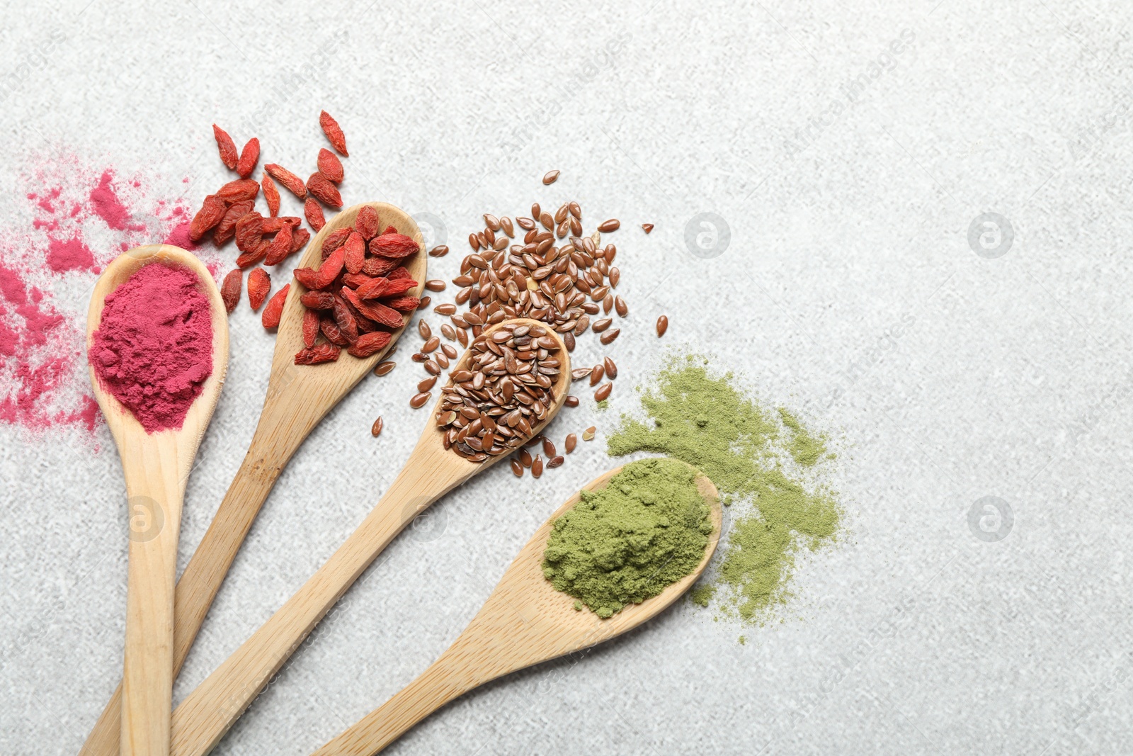 Different superfood powders in spoons on light grey table, flat lay Photo of Different superfood powders in spoons on light grey table, flat lay
