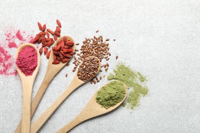 Photo of Different superfood powders in spoons on light grey table, flat lay