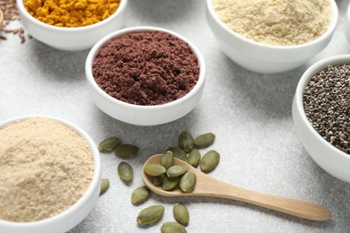 Photo of Different superfood powders on light grey table, closeup