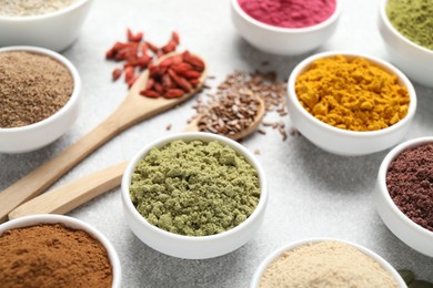Photo of Different superfood powders on light grey table, closeup