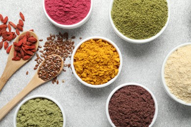 Photo of Different superfood powders on light grey table, flat lay