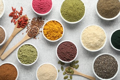Photo of Different superfood powders on light grey table, flat lay