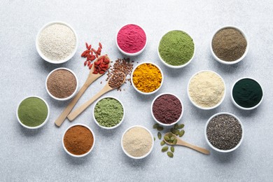 Photo of Different superfood powders on light grey table, flat lay