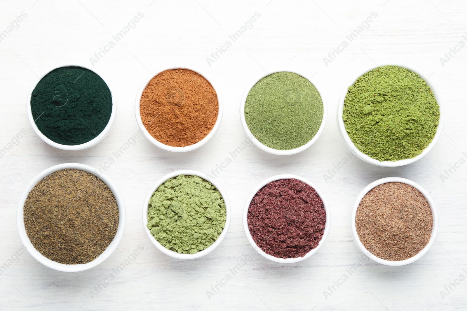 Different superfood powders on white wooden table, flat lay Photo of Different superfood powders on white wooden table, flat lay