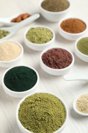 Photo of Different superfood powders on white wooden table, closeup