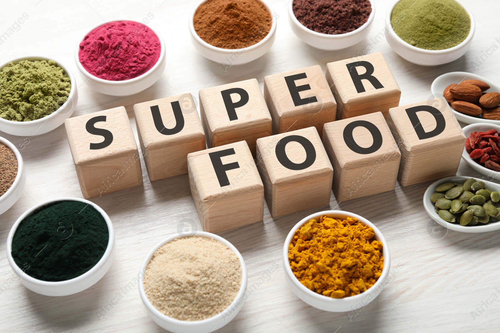 Different superfood powders and words made of cubes on white table, closeup Photo of Different superfood powders and words made of cubes on white table, closeup