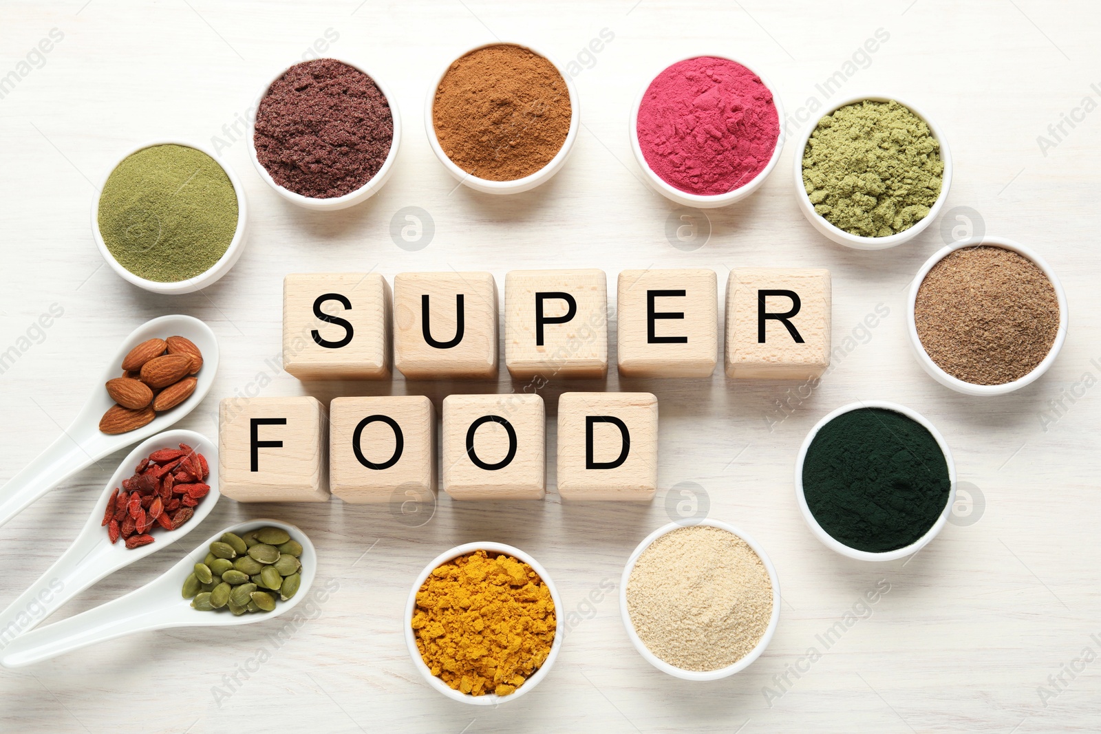 Different superfood powders and words made of cubes on white table, flat lay Photo of Different superfood powders and words made of cubes on white table, flat lay