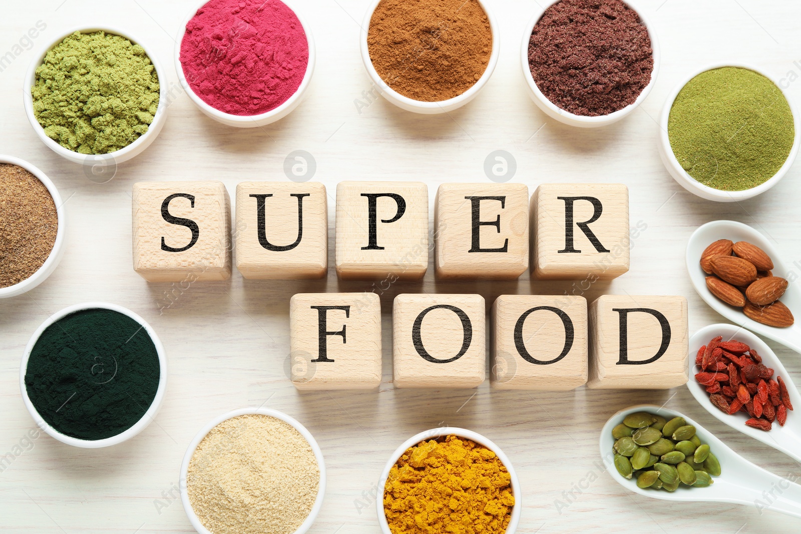 Different superfood powders and words made of cubes on white table, flat lay Photo of Different superfood powders and words made of cubes on white table, flat lay