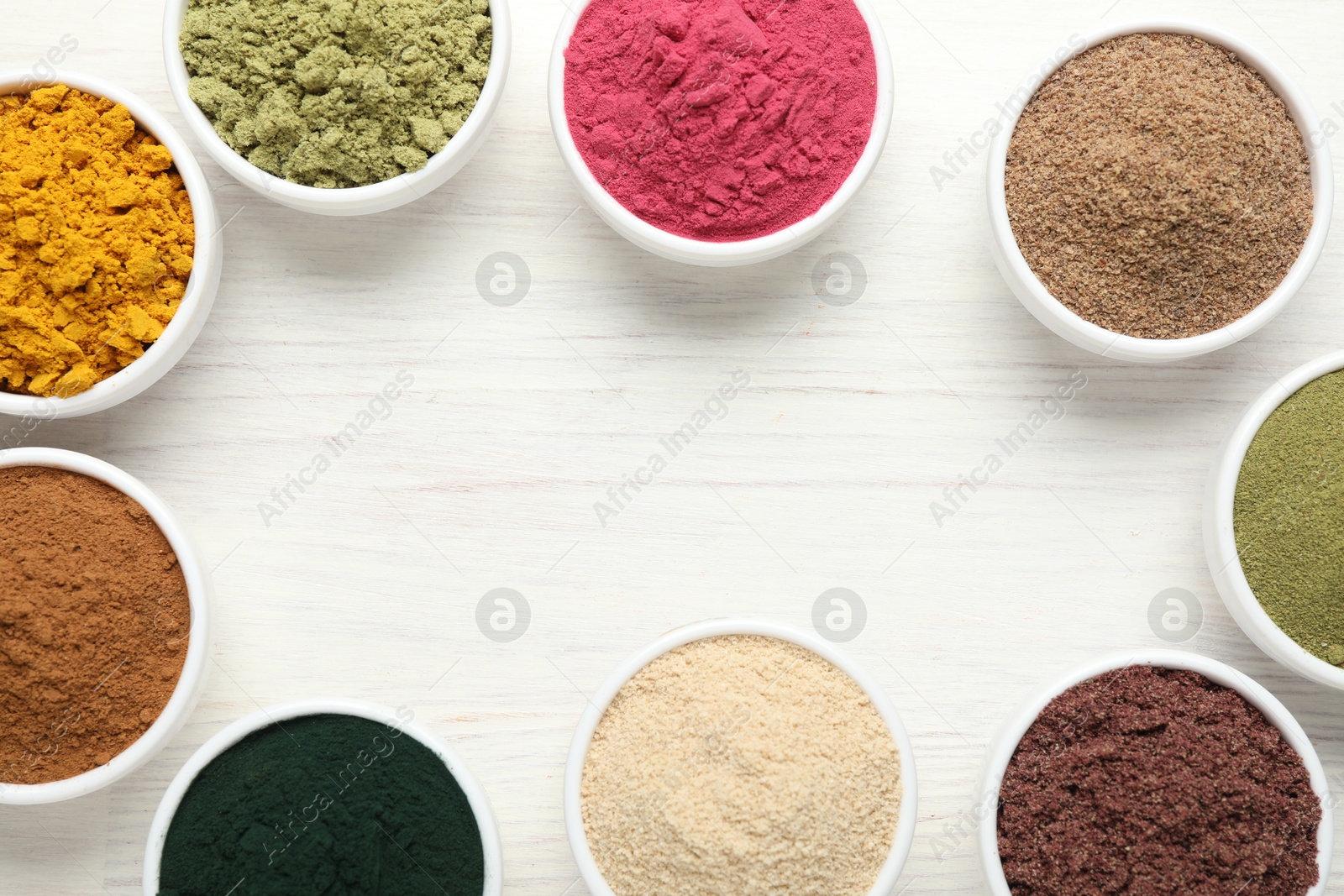 Photo of Frame of different superfood powders on white wooden table, flat lay. Space for text