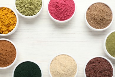 Photo of Frame of different superfood powders on white wooden table, flat lay. Space for text