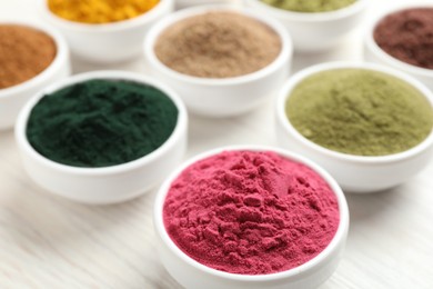 Photo of Different superfood powders on white wooden table, closeup