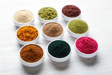 Photo of Different superfood powders on white wooden table, closeup