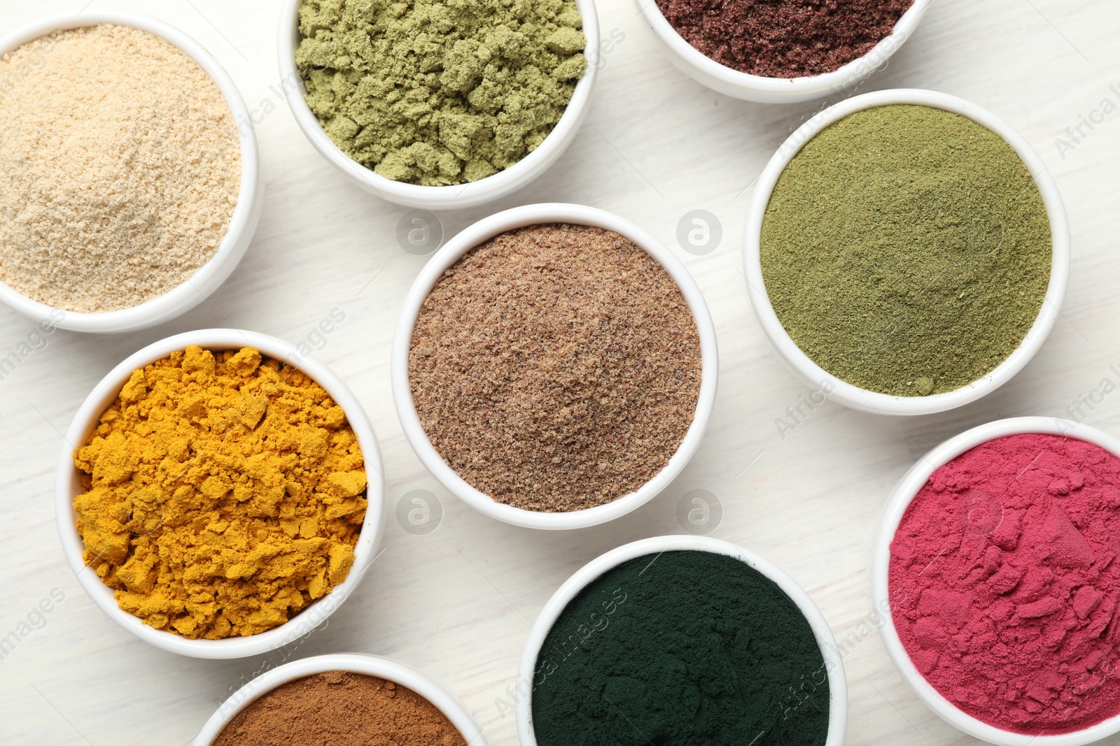 Different superfood powders on white wooden table, flat lay Photo of Different superfood powders on white wooden table, flat lay