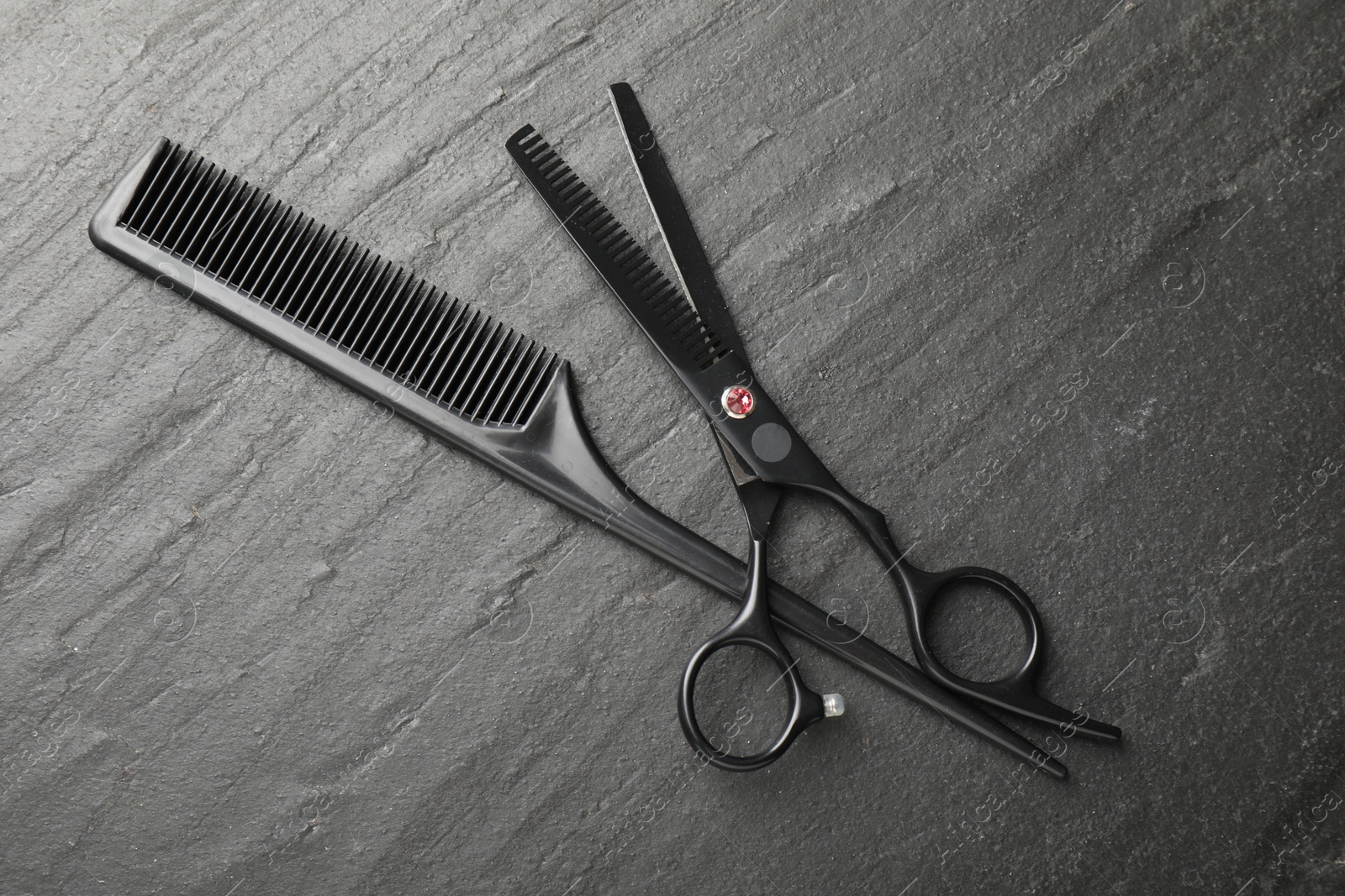 Comb and scissors on black table, flat lay. Hairdresser's tools Photo of Comb and scissors on black table, flat lay. Hairdresser's tools