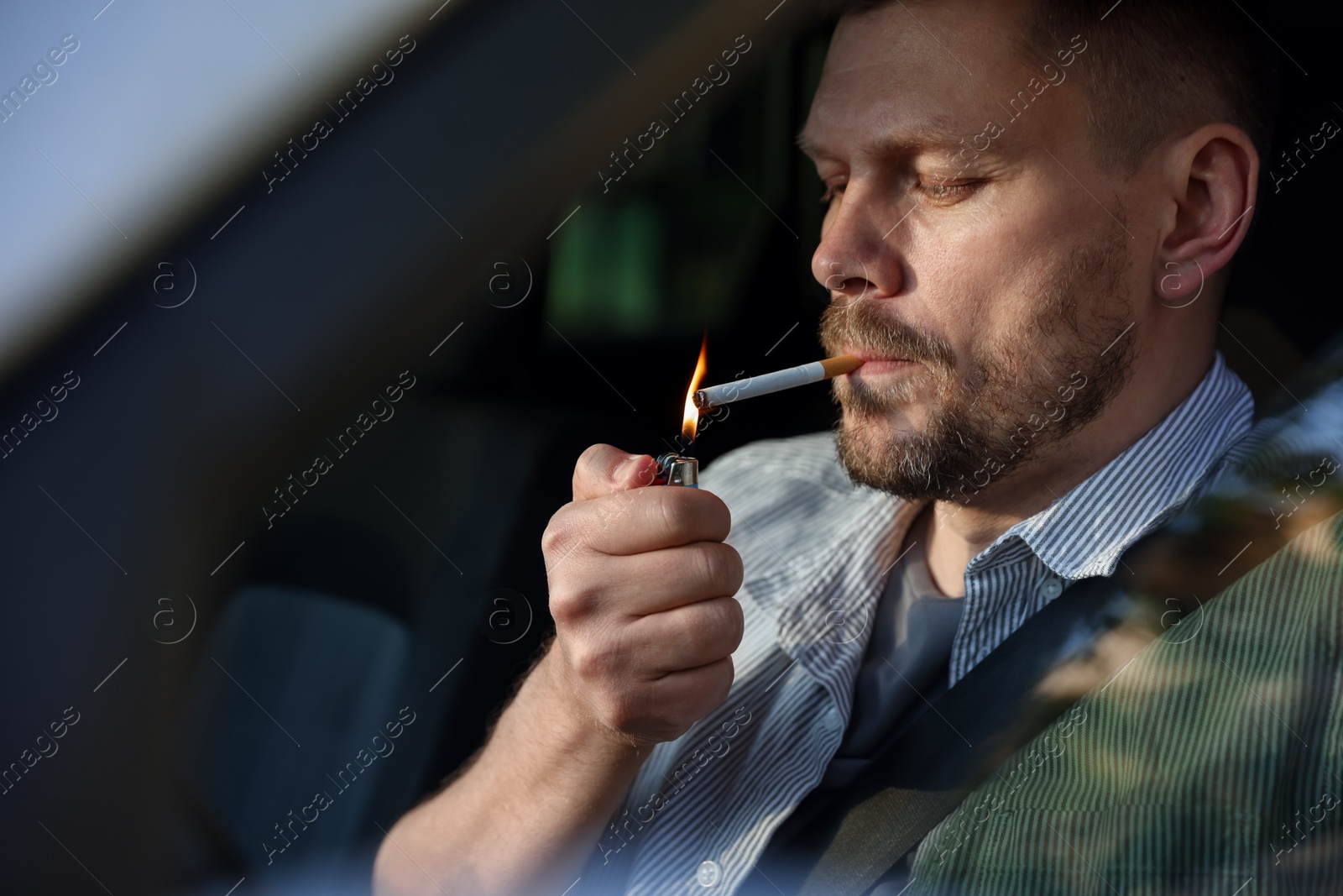 Man lighting cigarette in car, view from outside Photo of Man lighting cigarette in car, view from outside