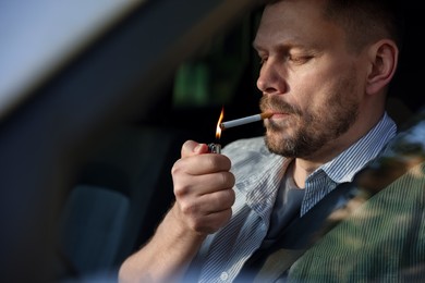Photo of Man lighting cigarette in car, view from outside