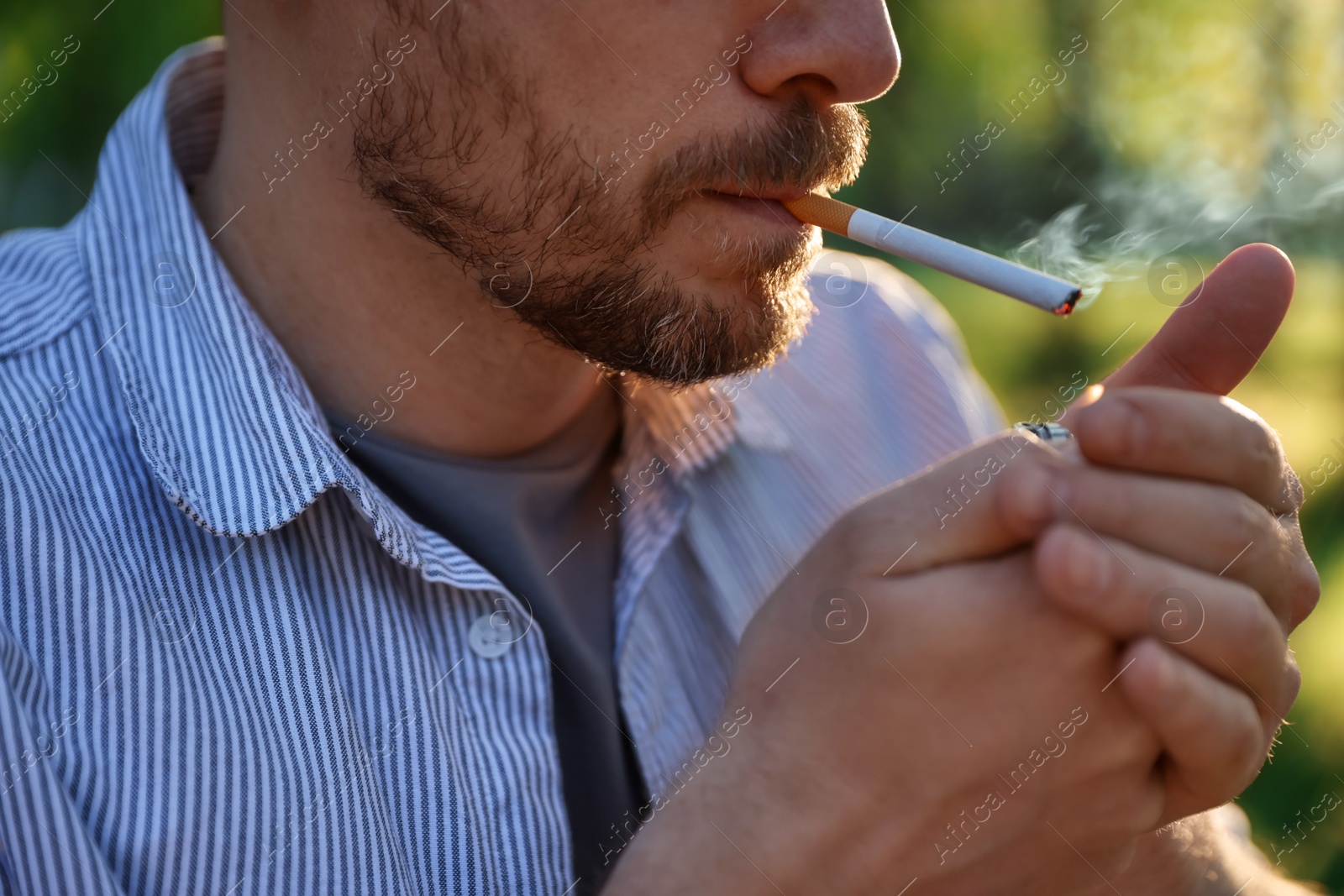 Man lighting cigarette with lighter outdoors, closeup Photo of Man lighting cigarette with lighter outdoors, closeup