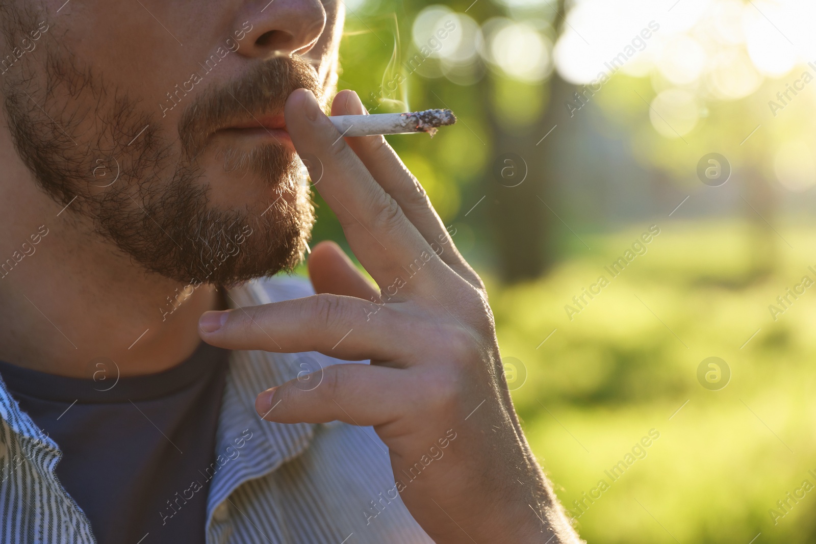 Man smoking cigarette outdoors, closeup. Space for text Photo of Man smoking cigarette outdoors, closeup. Space for text