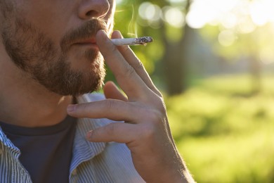 Photo of Man smoking cigarette outdoors, closeup. Space for text