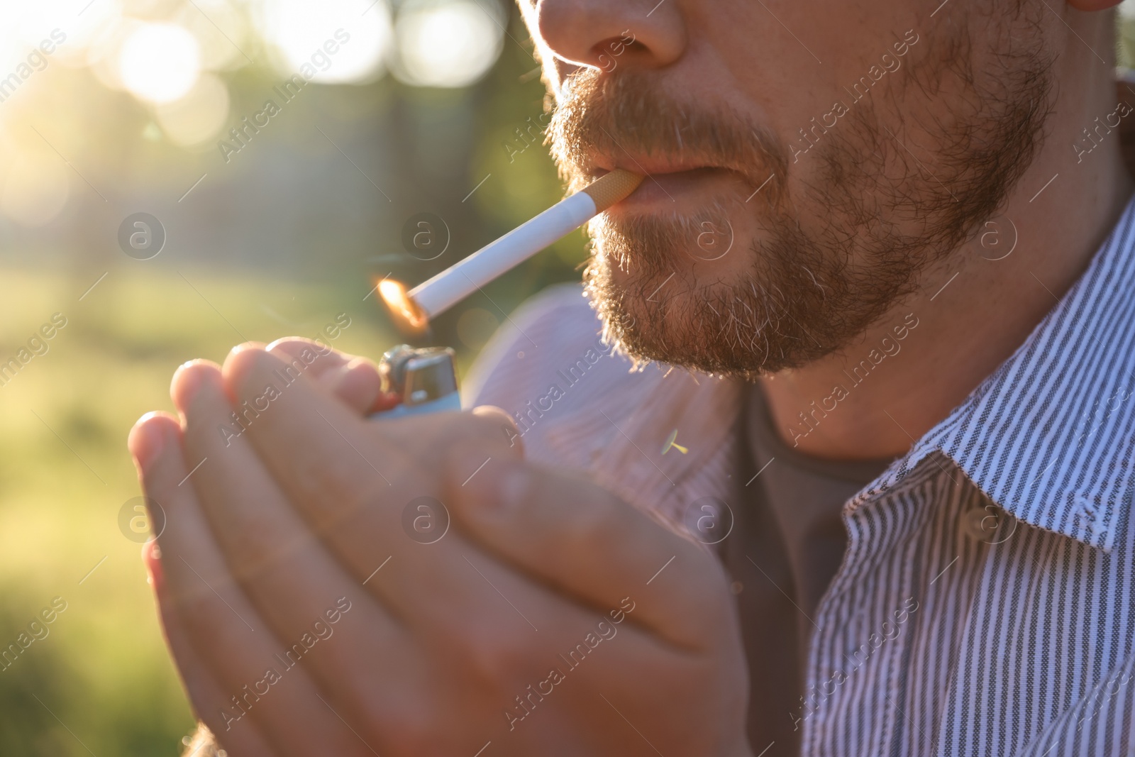 Man lighting cigarette with lighter outdoors, closeup Photo of Man lighting cigarette with lighter outdoors, closeup