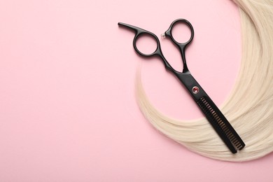 Photo of Hair strand and scissors on light pink background, top view. Space for text