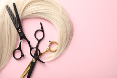 Photo of Hair strand and scissors on light pink background, top view. Space for text
