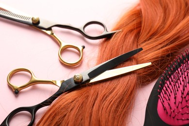 Photo of Hair strand and hairdresser's tools on light pink background, closeup