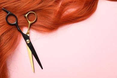 Photo of Hair strand and scissors on light pink background, top view. Space for text