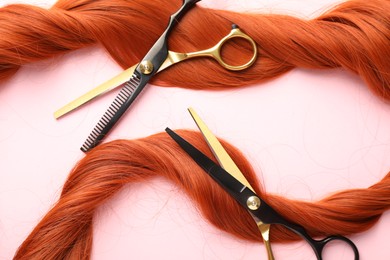 Photo of Hair strand and scissors on light pink background, top view