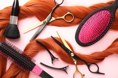Photo of Hair strand and hairdresser's tools on light pink background, flat lay