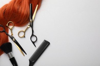 Photo of Hair strand and hairdresser's tools on light background, flat lay. Space for text