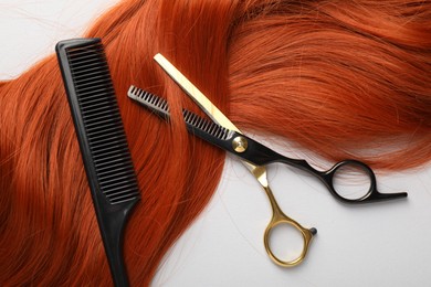 Photo of Hair strand and hairdresser's tools on light background, flat lay