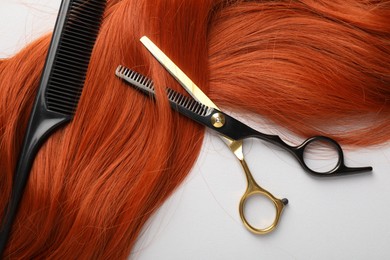 Photo of Hair strand and hairdresser's tools on light background, flat lay