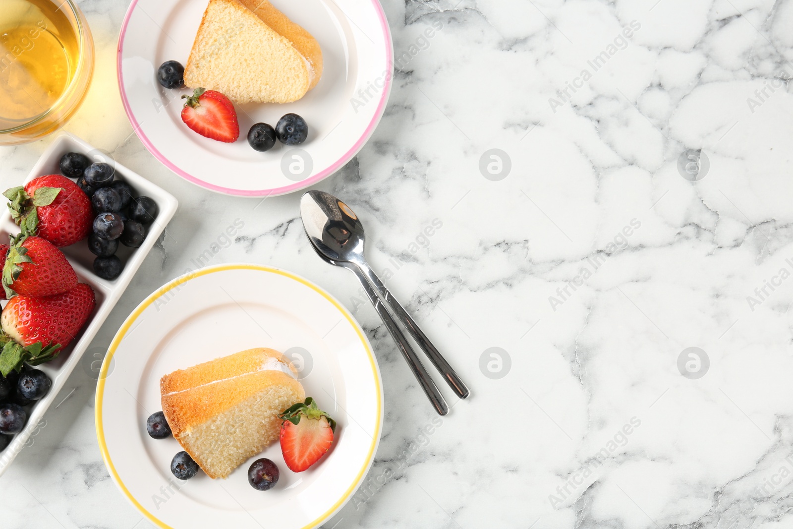 Pieces of tasty bundt cake with berries and tea on white marble table, flat lay. Space for text Photo of Pieces of tasty bundt cake with berries and tea on white marble table, flat lay. Space for text