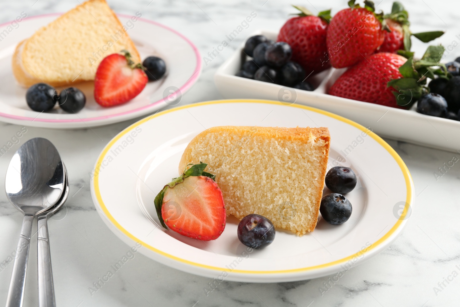 Pieces of tasty bundt cake with berries on white marble table, closeup Photo of Pieces of tasty bundt cake with berries on white marble table, closeup